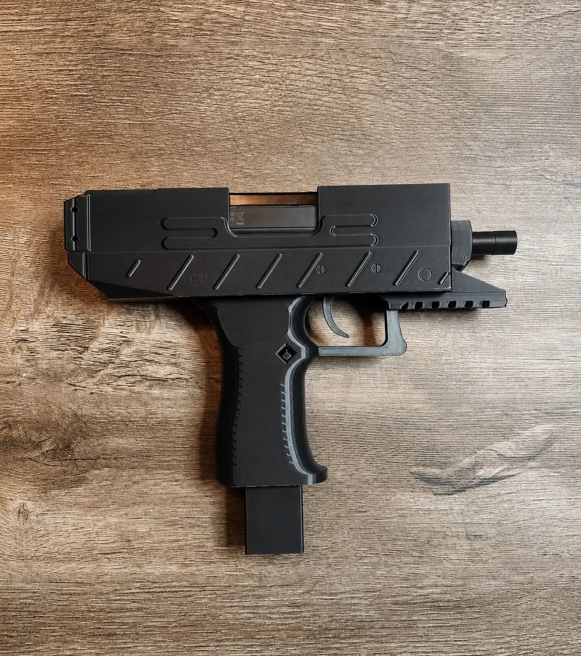 La carcasa UZI, negra, sobre una mesa de madera.